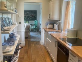 A kitchen with shelves of dishes and a sink at Maple Cottage in Buckland Newton near Dorchester