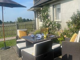 A garden dining setup with a table, chairs, and umbrella at Maple Cottage Buckland Newton near Dorchester