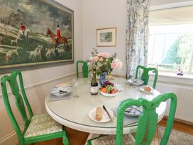 A dining room with a round table set with plates and a wine bottle at Maple Cottage Buckland Newton near Dorchester