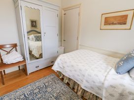 A bedroom with a bed, wardrobe, and chair at Maple Cottage in Buckland Newton near Dorchester