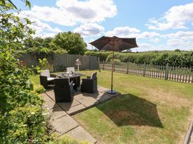 A garden with a table and chairs under an umbrella at Maple Cottage Buckland Newton near Dorchester