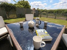 An outdoor table with a teapot, french press, cups, and a book at Maple Cottage Buckland Newton near Dorchester