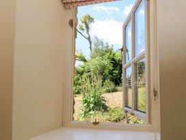 A view of plants and grass through an open window at Upper Mill Barn, Coln St Aldwyns, near Bibury