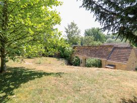 A garden with trees and a building at Upper Mill Barn in Coln St Aldwyns near Bibury