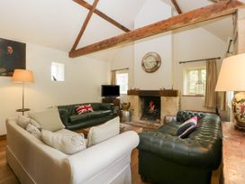 A living room with leather sofas a fireplace and wooden beams at Hazel Manor Wing in Painswick