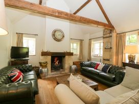 A living room with two green leather sofas a beige sofa a wooden coffee table a fireplace and a television at Hazel Manor Wing in Painswick