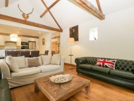 A living room with two sofas a wooden coffee table and exposed wooden ceiling beams at Hazel Manor Wing in Painswick