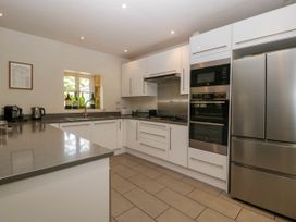 A kitchen with white cabinets stainless steel appliances and a window with bottles on the sill at Hazel Manor Wing in Painswick