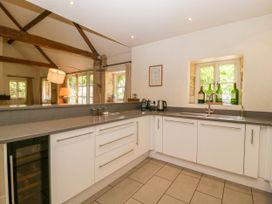 A kitchen with white cabinets a gray countertop a sink a kettle and bottles on a windowsill at Hazel Manor Wing in Painswick