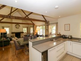 An open plan kitchen and dining area with wooden beams and a living room with a fireplace at Hazel Manor Wing in Painswick