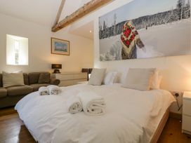 A bedroom with a bed and rolled towels with a sofa and dresser at Hazel Manor Wing in Painswick