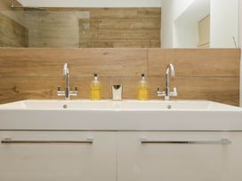A bathroom with a double sink and two soap dispensers with wooden panel wall at Hazel Manor Wing in Painswick