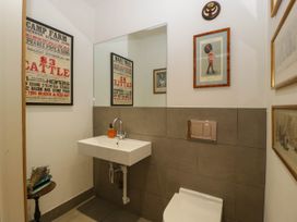A small bathroom with a wall-mounted sink a toilet a mirror and framed pictures at Hazel Manor Wing in Painswick