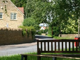 A view of a road with a bench and a stone wall at Elm View in Chipping Campden