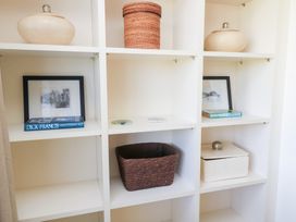 A shelf with books, framed pictures, and containers at Fairview Cottage in Milton-Under-Wychwood