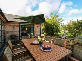 An outdoor patio with a table and umbrella at Fairview Cottage Milton-Under-Wychwood