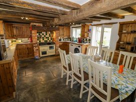 A kitchen with wooden cabinets and a dining table at Elmhurst Cottage in Lower Quinton