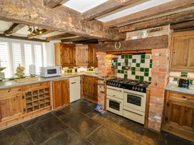 A kitchen with cabinets, stove, and microwave at Elmhurst Cottage in Lower Quinton
