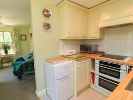 A kitchen with cream cabinets a small white fridge a microwave oven and a double oven at Garden Cottage Black Bourton near Burford
