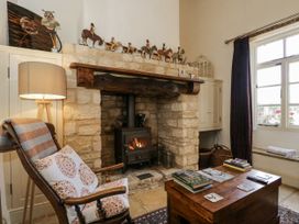 A living room with a fireplace and armchair at The Old Reading Room in Bledington near Stow-on-the-Wold