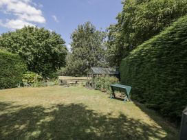A garden with a greenhouse and seating area at The Old Reading Room Bledington near Stow-on-the-Wold