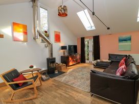 A living room with a sofa, coffee table, and television at The Linhay in Little Coxwell near Faringdon