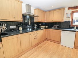 A kitchen with wooden cabinets and appliances at Tithe Barn, Lyneham