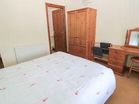 A bedroom with a bed, wardrobe, desk and mirror at Tithe Barn, Lyneham