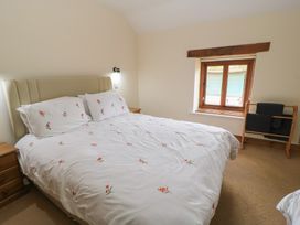 A bedroom with a bed and window at Tithe Barn, Lyneham