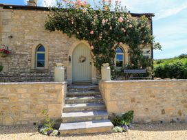 A stone cottage entrance with flowers and steps at Cider Press Cottage in Priston Village, Bath