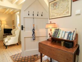 A living room with a desk books and a lamp at Cider Press Cottage in Priston Village, Bath