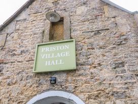 A sign for Priston Village Hall on a stone wall at Cider Press Cottage Priston Village, Bath