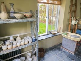 A kitchen with pottery on a shelf and a sink at Bridge Studio Near Broad Chalke