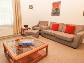 A living room with a sofa, an armchair, and a coffee table with a Monopoly game at Rojoy in Salisbury