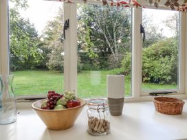 A kitchen with a garden view featuring fruit in a bowl and a vase at Droop Farm Cottage in Droop near Hazelbury Bryan