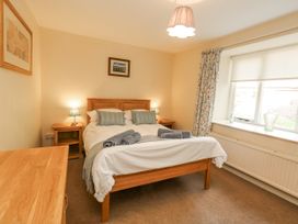 A bedroom with a bed, nightstand, and window at Droop Farm Cottage in Droop near Hazelbury Bryan