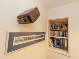 A bookshelf with books and a framed picture at Droop Farm Cottage in Droop near Hazelbury Bryan