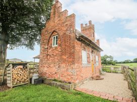A brick building with a wooden door and stone pathway at The Shooting Folly in Cheswardine