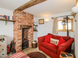 A snug with a brick fireplace and couch at The Shooting Folly in Cheswardine