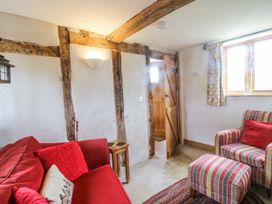 A living room with a red sofa and striped chair at The Shooting Folly in Cheswardine
