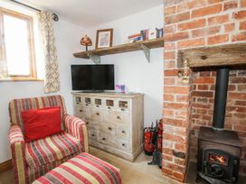 A living room with a television and wooden furniture at The Shooting Folly in Cheswardine