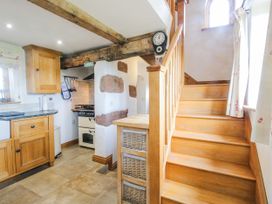 A kitchen with wooden cabinets and stairs at The Shooting Folly in Cheswardine