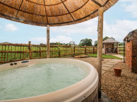 A hot tub with a thatched roof and a garden house at The Shooting Folly in Cheswardine