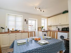 A kitchen with a table set for four with croissants on a plate at Honeysuckle Cottage in Condicote