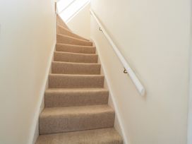 A carpeted stairway with a white handrail on the right side at Honeysuckle Cottage in Condicote