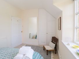 A bedroom with a chair a mirror folded towels and a window at Honeysuckle Cottage in Condicote