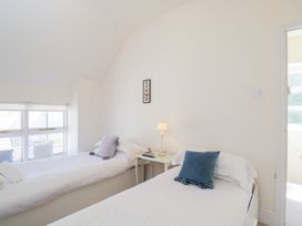 A bedroom with two single beds white bedding and pillows a small table with a lamp between beds at Honeysuckle Cottage in Condicote