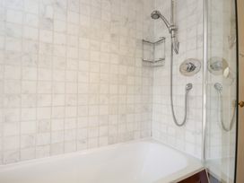 A bathroom with a bathtub and wall-mounted showerhead above at Honeysuckle Cottage in Condicote