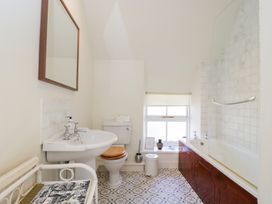 A bathroom with a white sink toilet and bathtub with tiled walls and patterned floor at Honeysuckle Cottage in Condicote