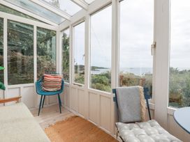 A conservatory with windows and seating at Greeb Rocks Cottage in Marazion